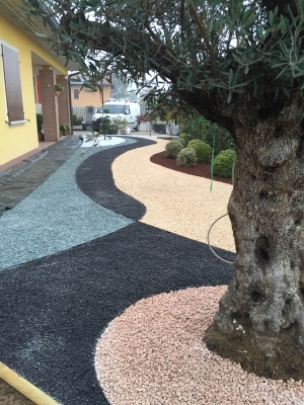Realizzazione Spazio Verde Esterno Con Ghiaie Colorate Ed Olivo In Primo Piano 